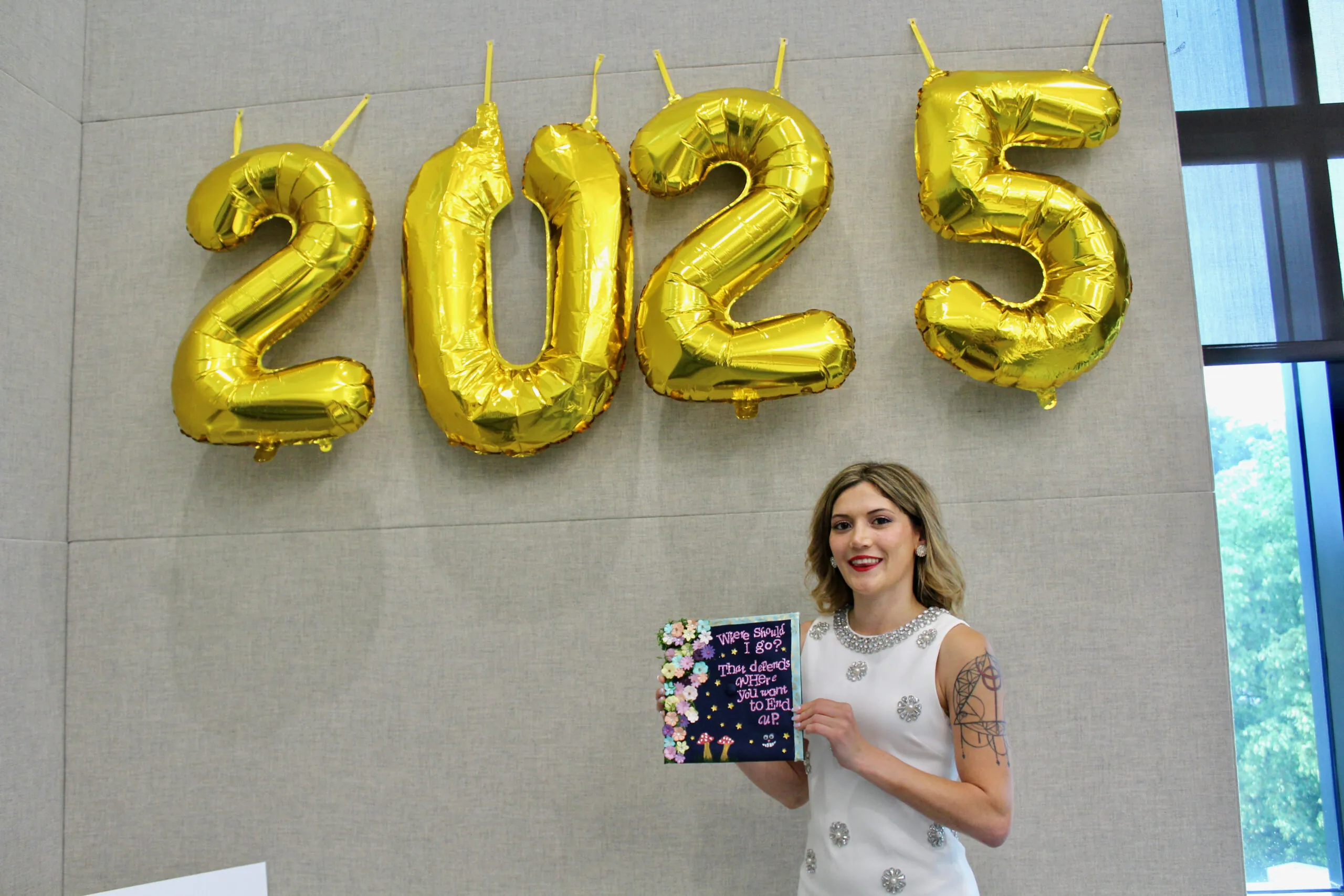 Student posing with graduation cap in front of balloons