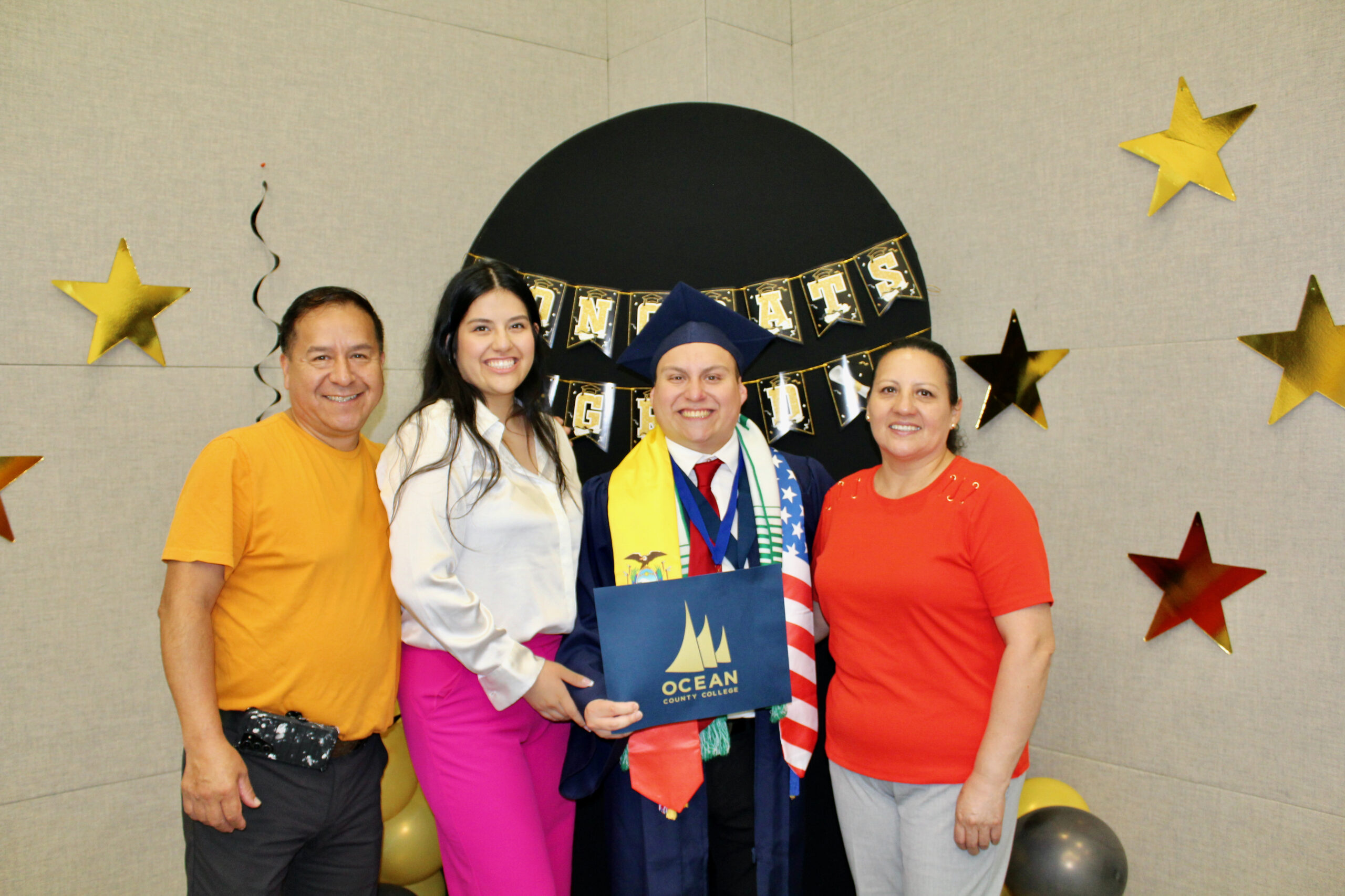 student in cap & gown posing with their family 