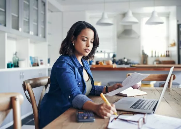 Woman working at a kitchen table on her laptop