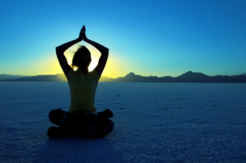 person meditating on the beach at sunrise
