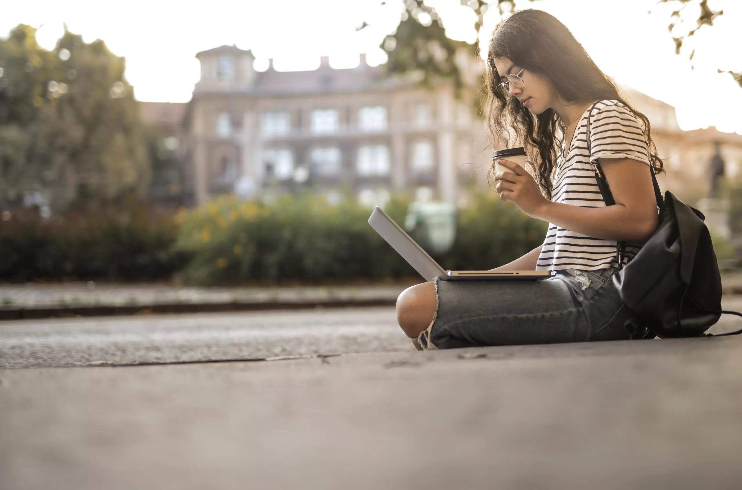 woman using laptop while drinking a coffee